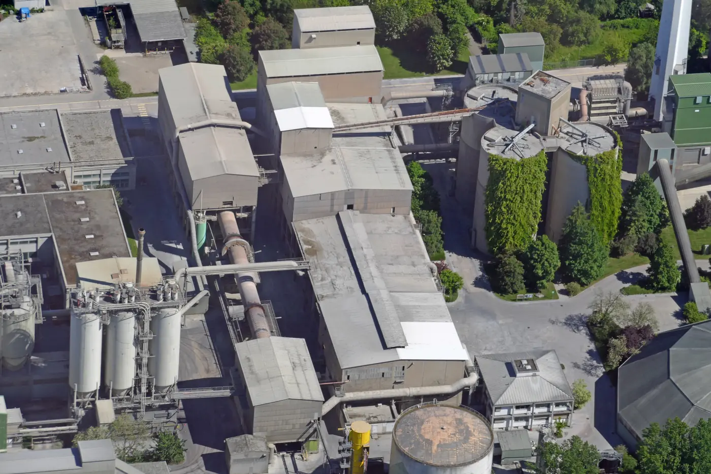 Aerial view of the Leimen cement works, with a long cylindrical rotary kiln between industrial buildings.
