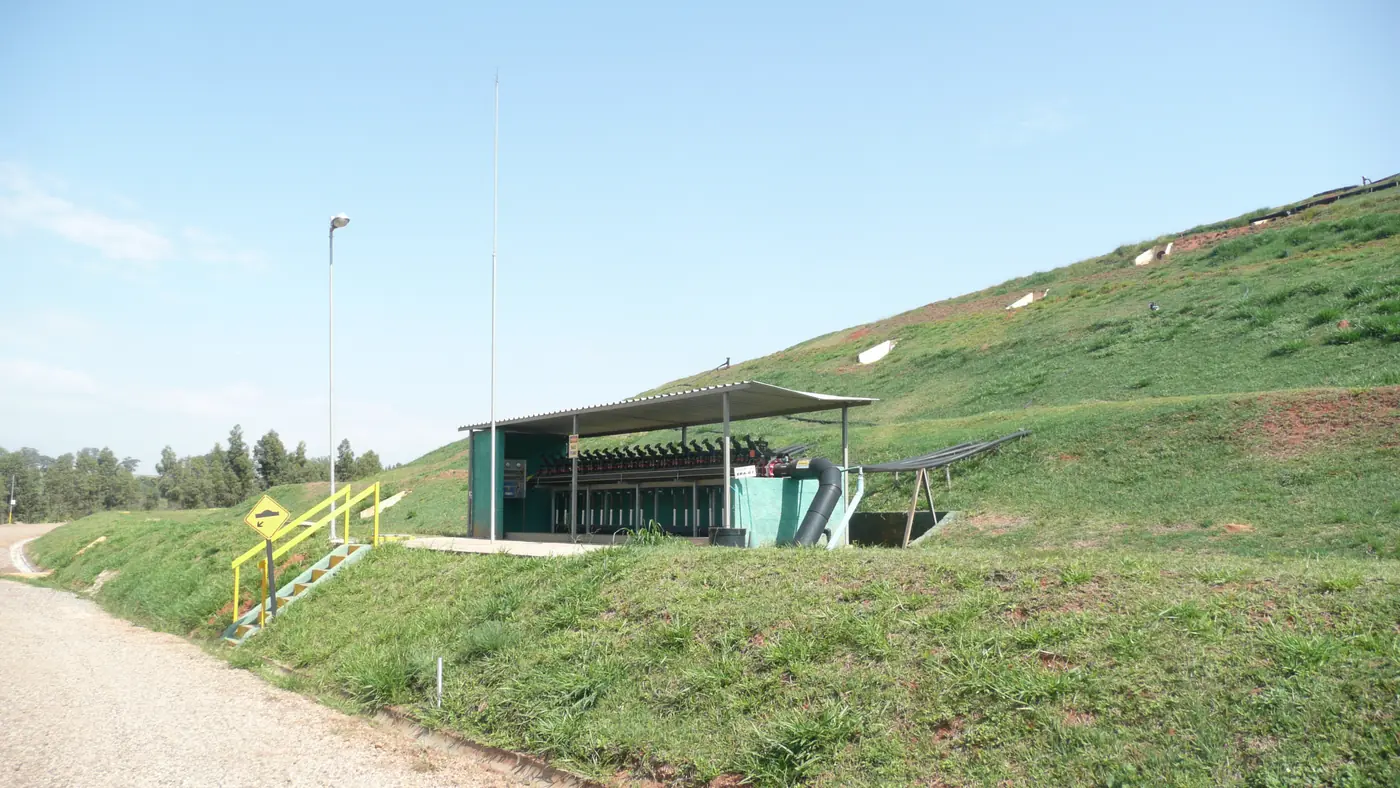 Gas collection pipes leading from a grass-covered landfill slope to a roofed installation