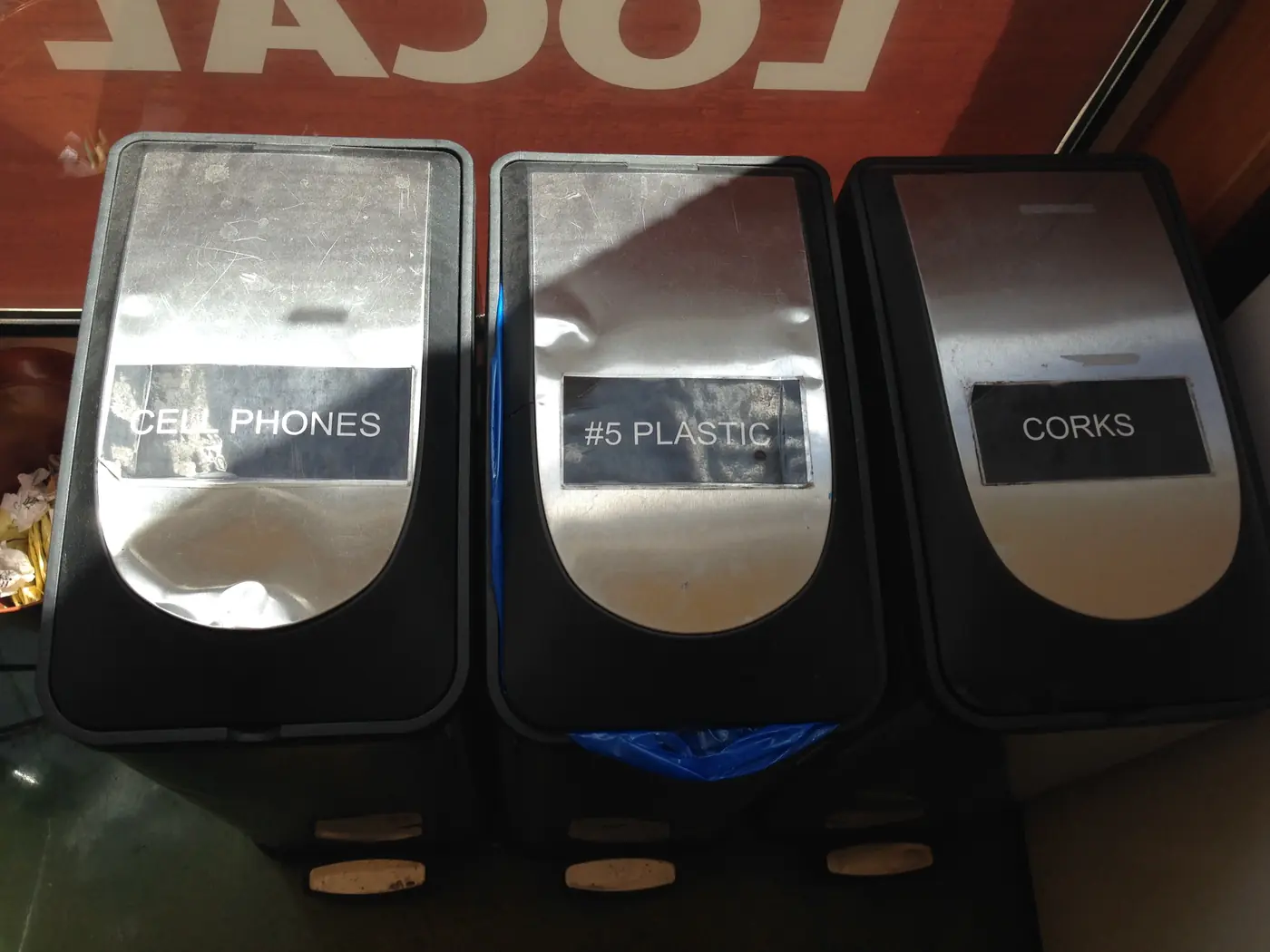 Separate collection bins labelled for cell phones, number five plastic and corks.